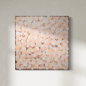 An orange, salmon, coral and pink abstract painting hangs on a white wall. 