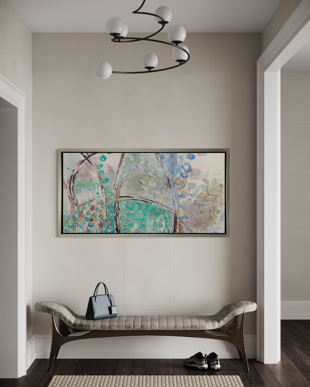 A teal, beige and mauve abstract landscape print in a silver floater frame hangs on a white wall above a modern gray upholstered bench with a small tote bag and a pair of sneakers on the floor.
