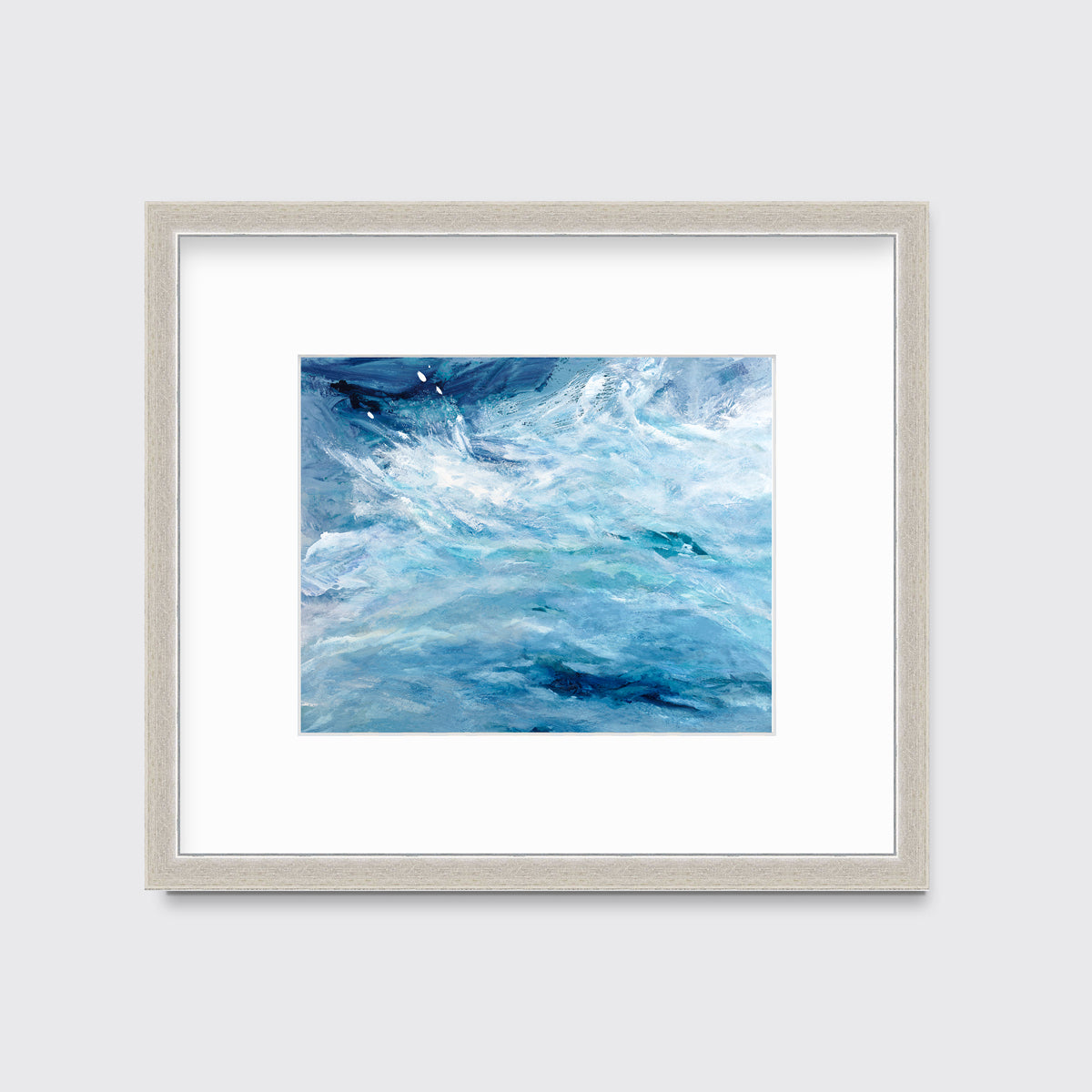 A blue, teal and white abstract print in a silver frame with a mat hangs on a white wall.