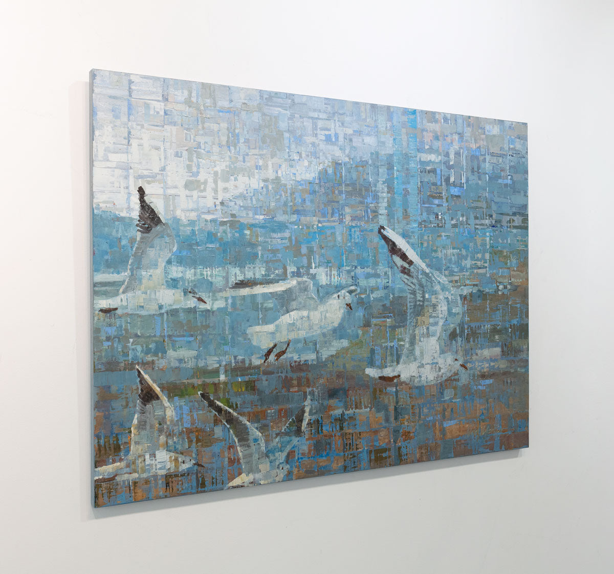 A painting on recycled metal print plates depicting seagulls in flight is seen at an angle on a gallery wall.