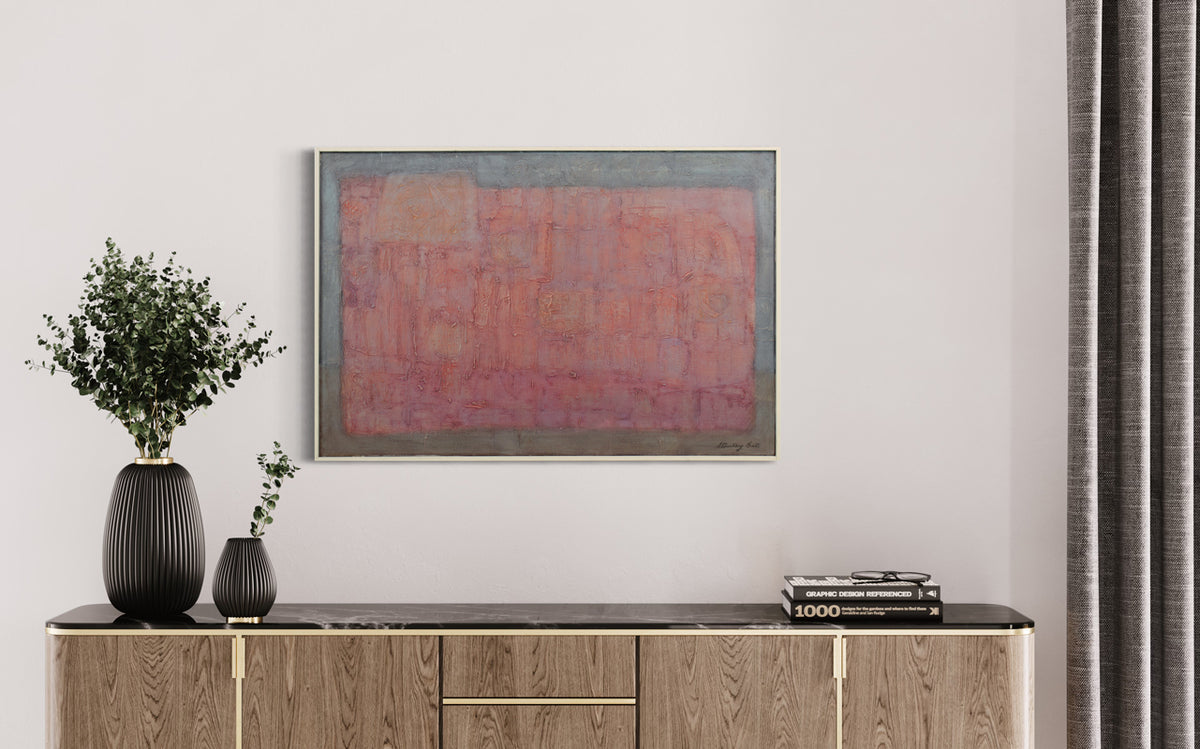 An abstract red and grey painting by Stanley Bate hangs on a white wall above a modern console table with black table decor and next to warm grey curtains. 