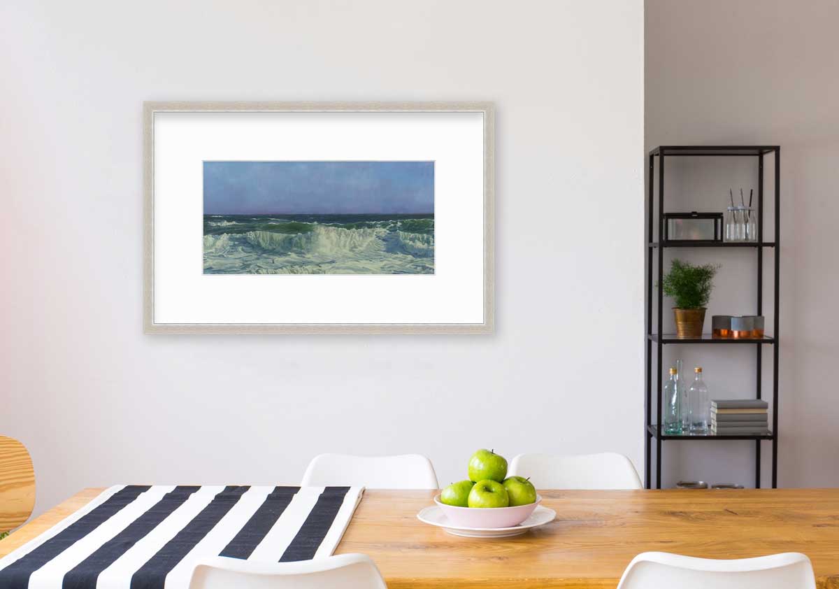 A blue, teal, white and light green abstract water wave print in a silver frame with a mat hangs on a white wall above a wood table with a blue and white striped table runner, a bowl of green apples and four white chairs.