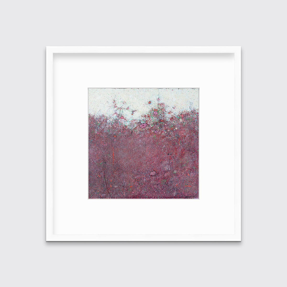 A dark red abstract landscape print in a white frame with a mat hangs on a white wall.