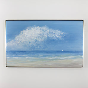 A contemporary seascape painting with clouds, water and a sailboat hangs on a white wall.