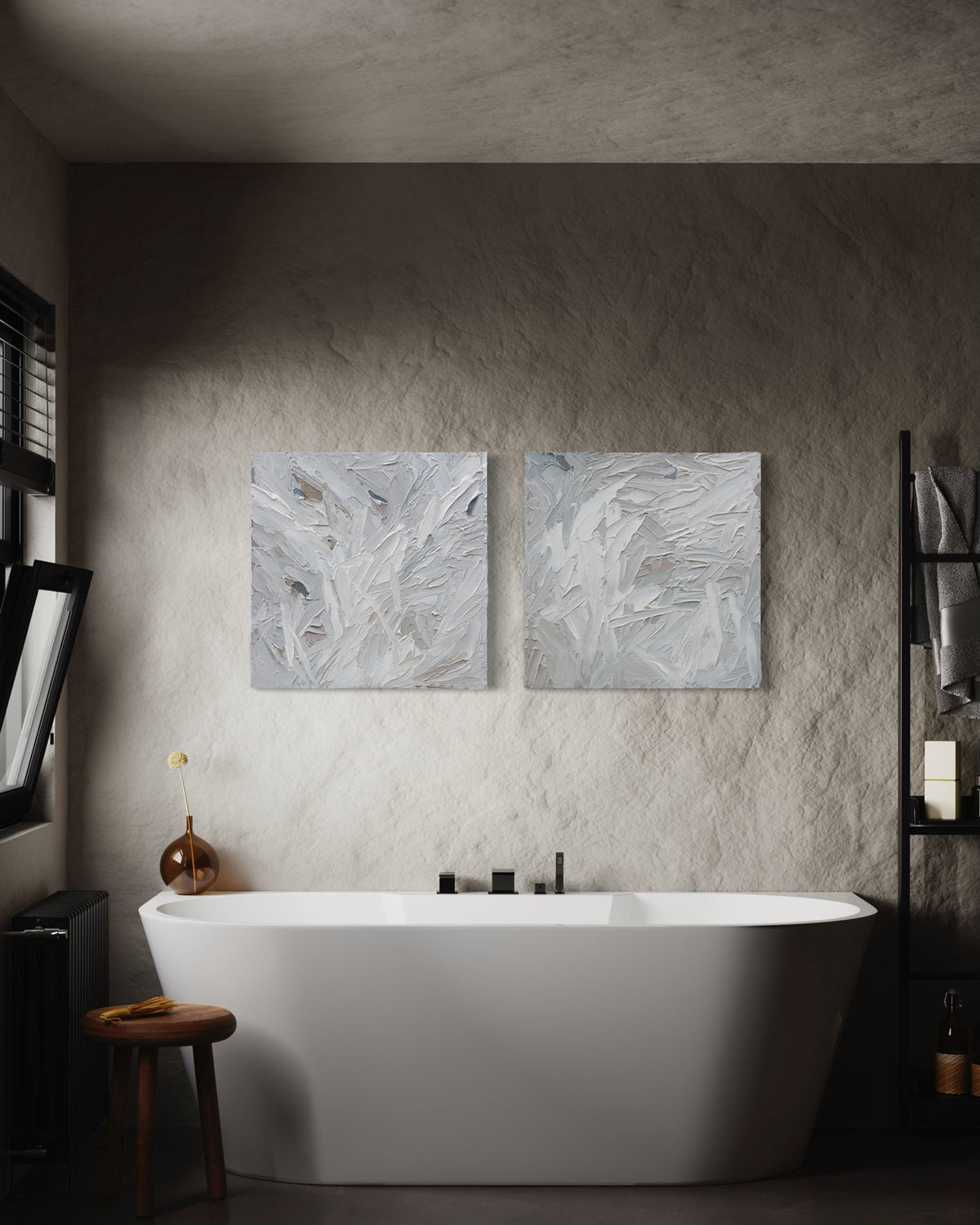 A pair of thickly textured paintings in grey, white, blue grey and plum grey by Teodora Guererra hanging on a wall in front of a modern bath tub.