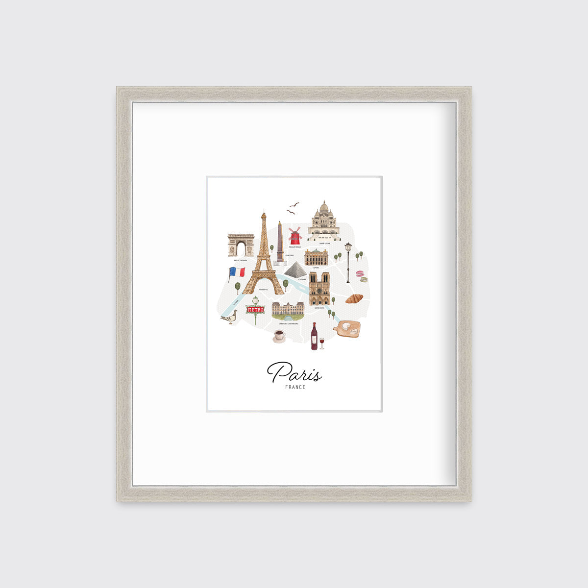 A multicolored map print of Paris, France with the famous landmarks in a silver frame with a mat hangs on a white wall.
