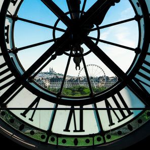 A photograph of a view from behind a large tower clock face looking out over Paris. 