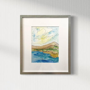 An abstract landscape matted and framed in a silver frame hangs on a white wall.