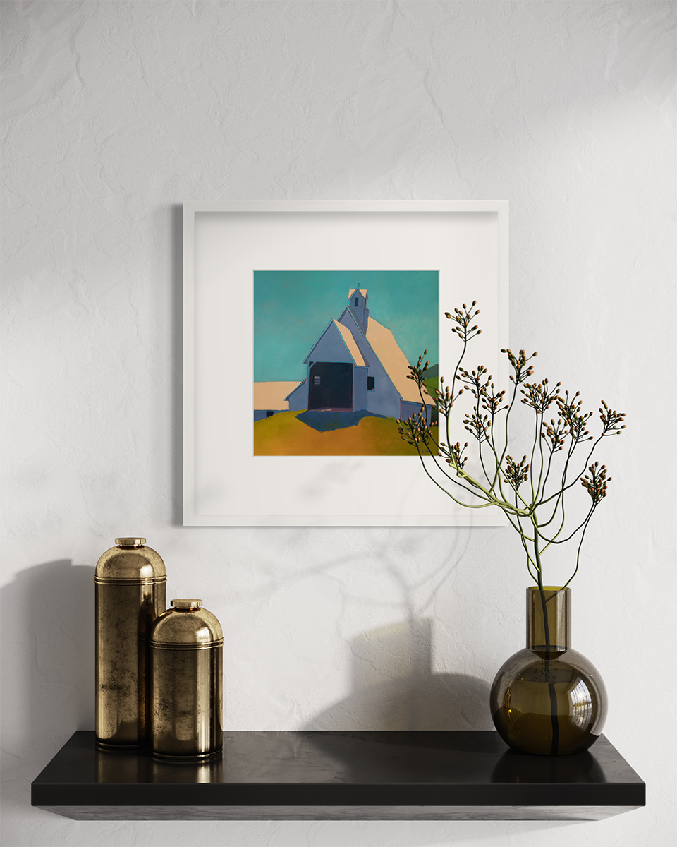 A teal, lavender, and peach contemporary barn print in a white frame with a mat hangs on a white wall above a small black floating shelf with two gold cylinders and a green glass vase with red berry stems.