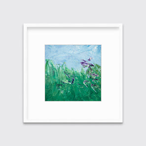 A blue, green and purple abstract landscape print in a white frame with a mat hangs on a white wall.