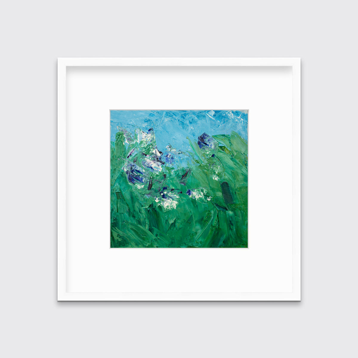 A blue, green, purple and white abstract landscape print in a white frame with a mat hangs on a white wall.