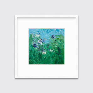 A blue, green, purple and white abstract landscape print in a white frame with a mat hangs on a white wall.