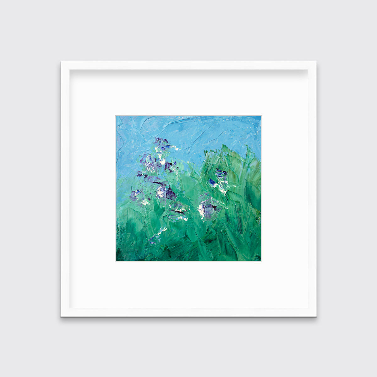 A blue, green, purple and white abstract landscape print in a white frame with a mat hangs on a white wall.