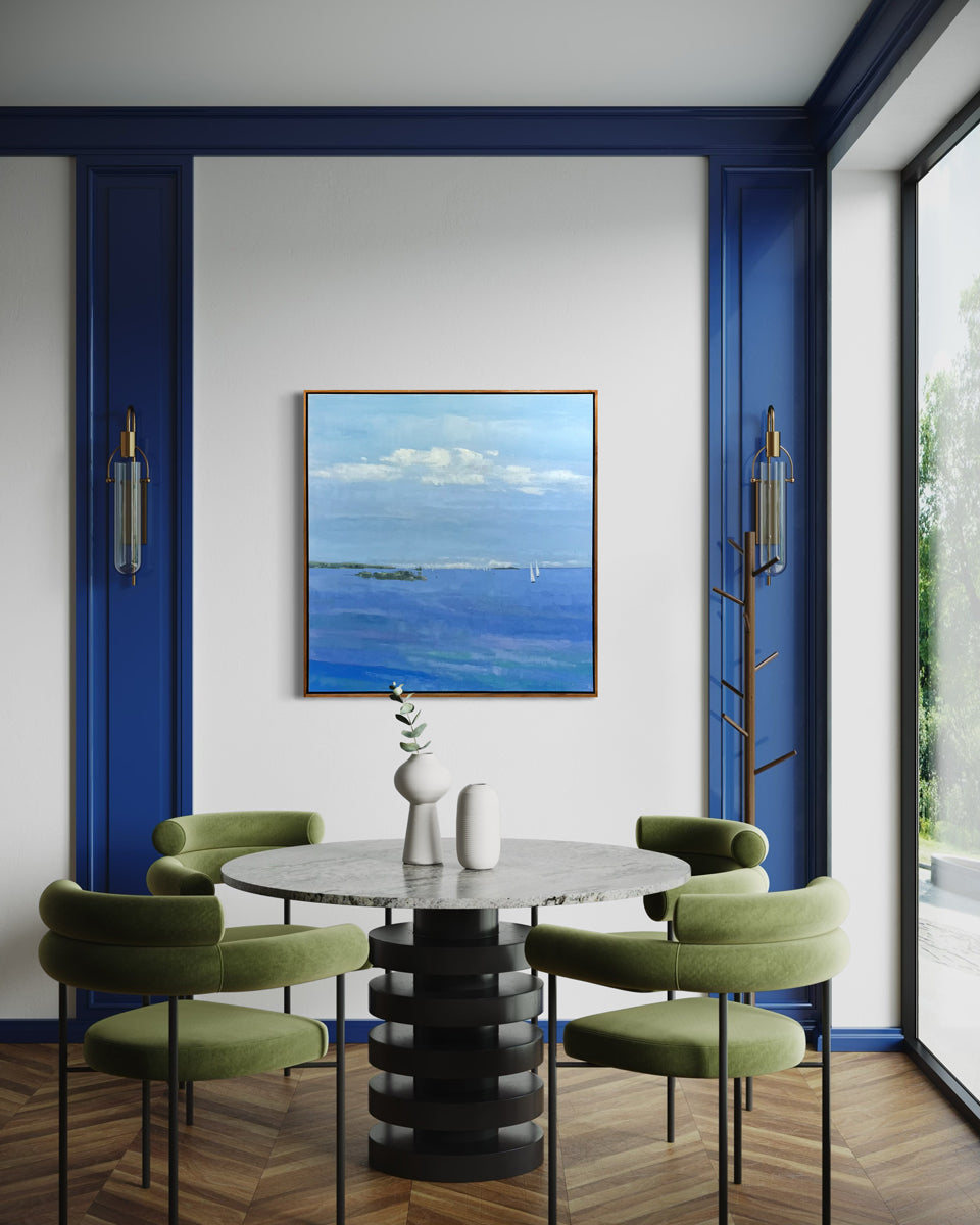 Modern dining room with a round table and green chairs, featuring a large ocean painting on the wall.