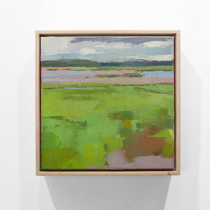 A blue and green framed textured abstracted landscape painting hangs on a white wall.