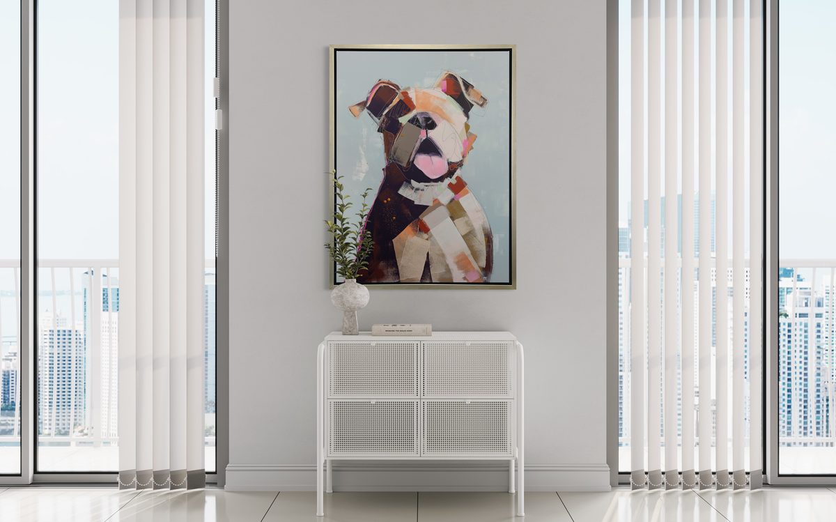 A light blue, orange, brown, pink and navy abstracted dog print in a silver floater frame hangs on a white wall above a white cabinet with a stone vase with flowers and a book.