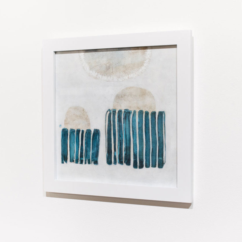 A blue, white, and beige abstract painting framed in a white frame hangs on a white wall.