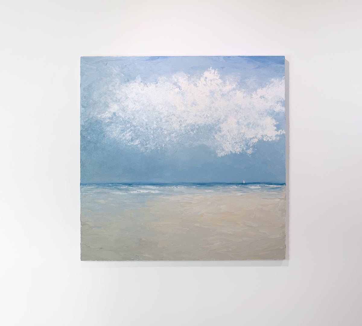 An abstract coastal seascape painting hangs on a white wall.