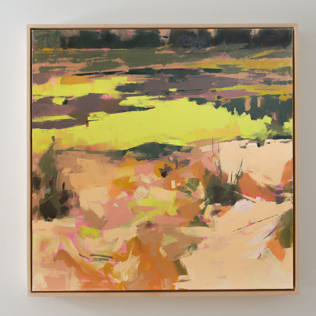  A yellow and orange abstract landscape painting hangs on a white wall.