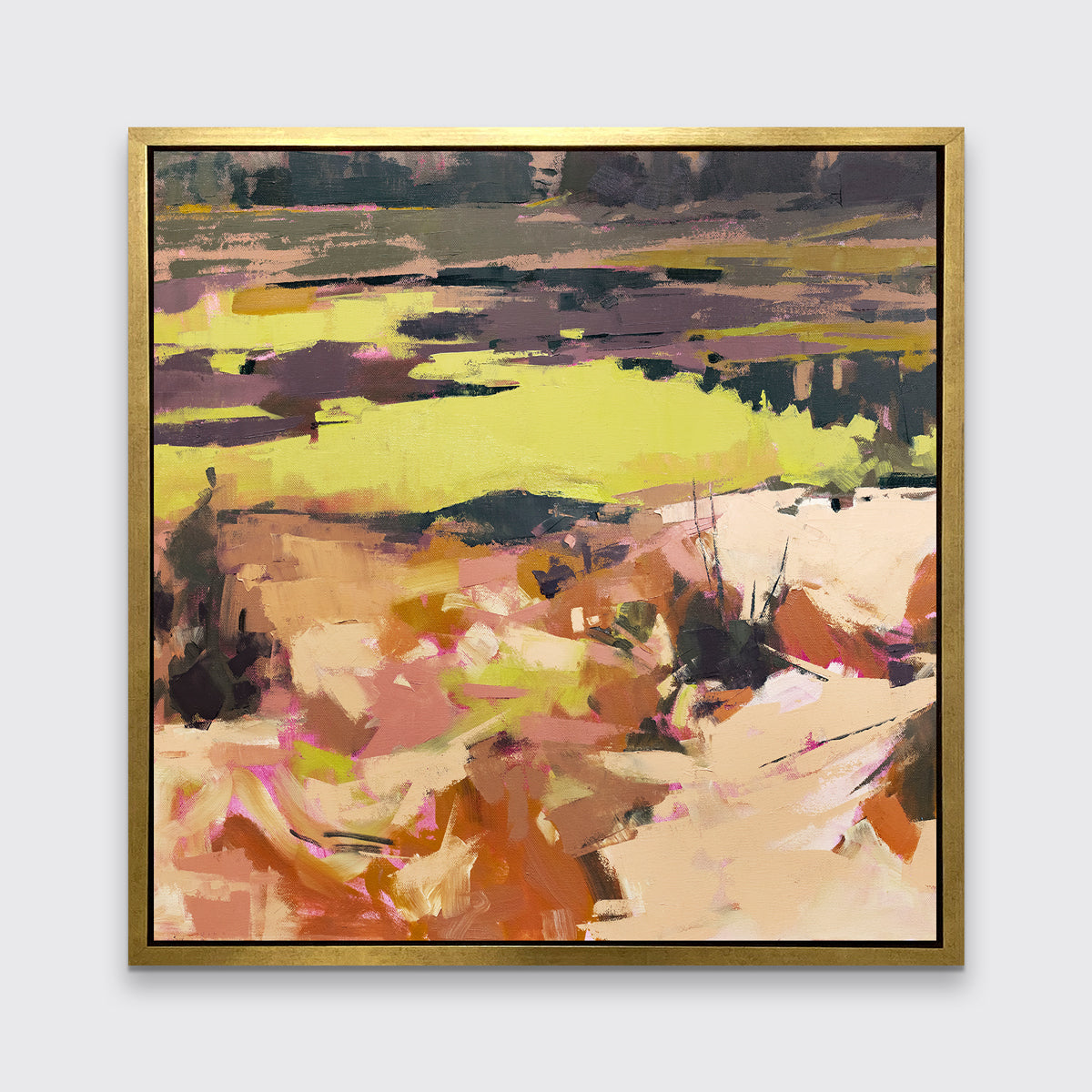 A yellow and orange abstracted landscape art print framed in a gold frame hangs on a white wall.