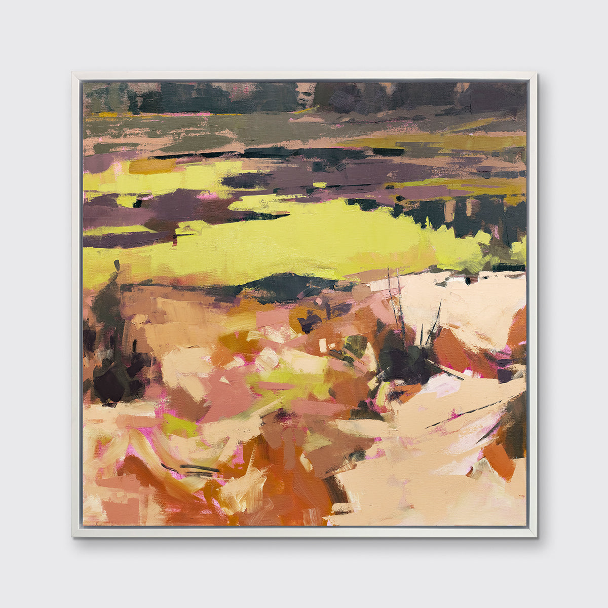 A yellow and orange abstracted landscape art print framed in a white frame hangs on a white wall.