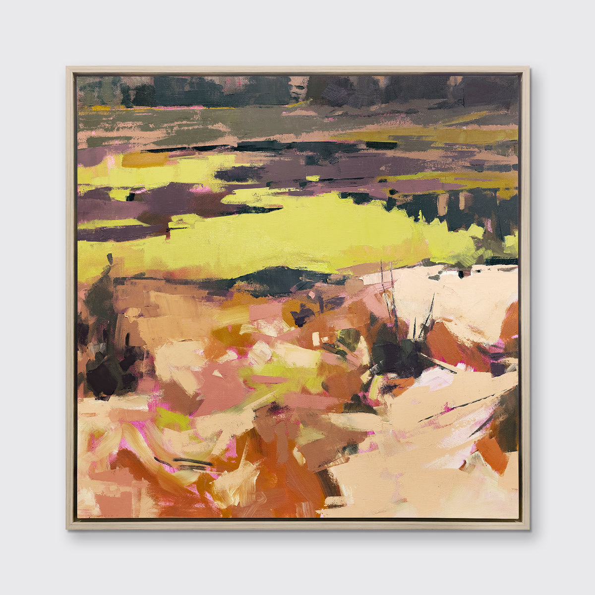 A yellow and orange abstracted landscape art print framed in a white oak frame hangs on a white wall.