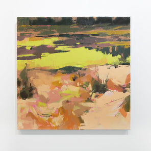 A yellow and orange abstract landscape painting hangs on a white wall. 