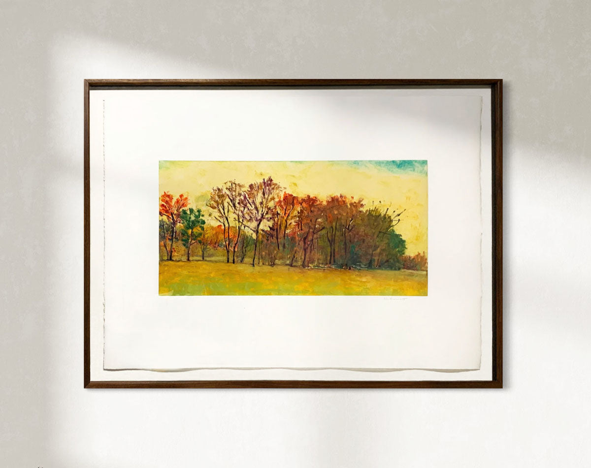 Framed painting of a landscape with trees and a yellow sky on a white wall.