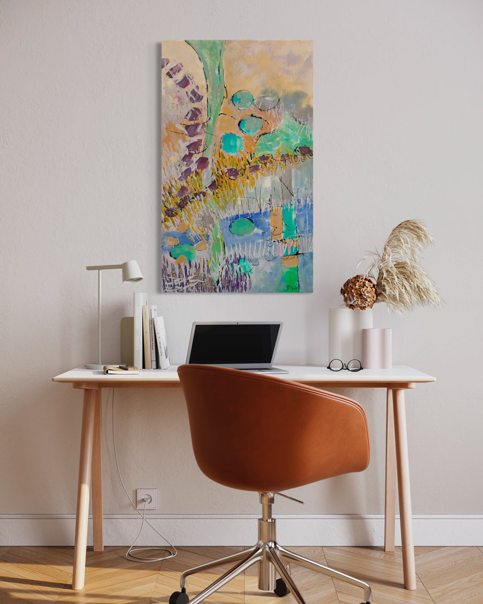 A colorful orange and turquoise abstract painting hangs on a light wall above a modern desk with books, a lap top, a table lamp, and decor, behind an orange swivel desk chair. 