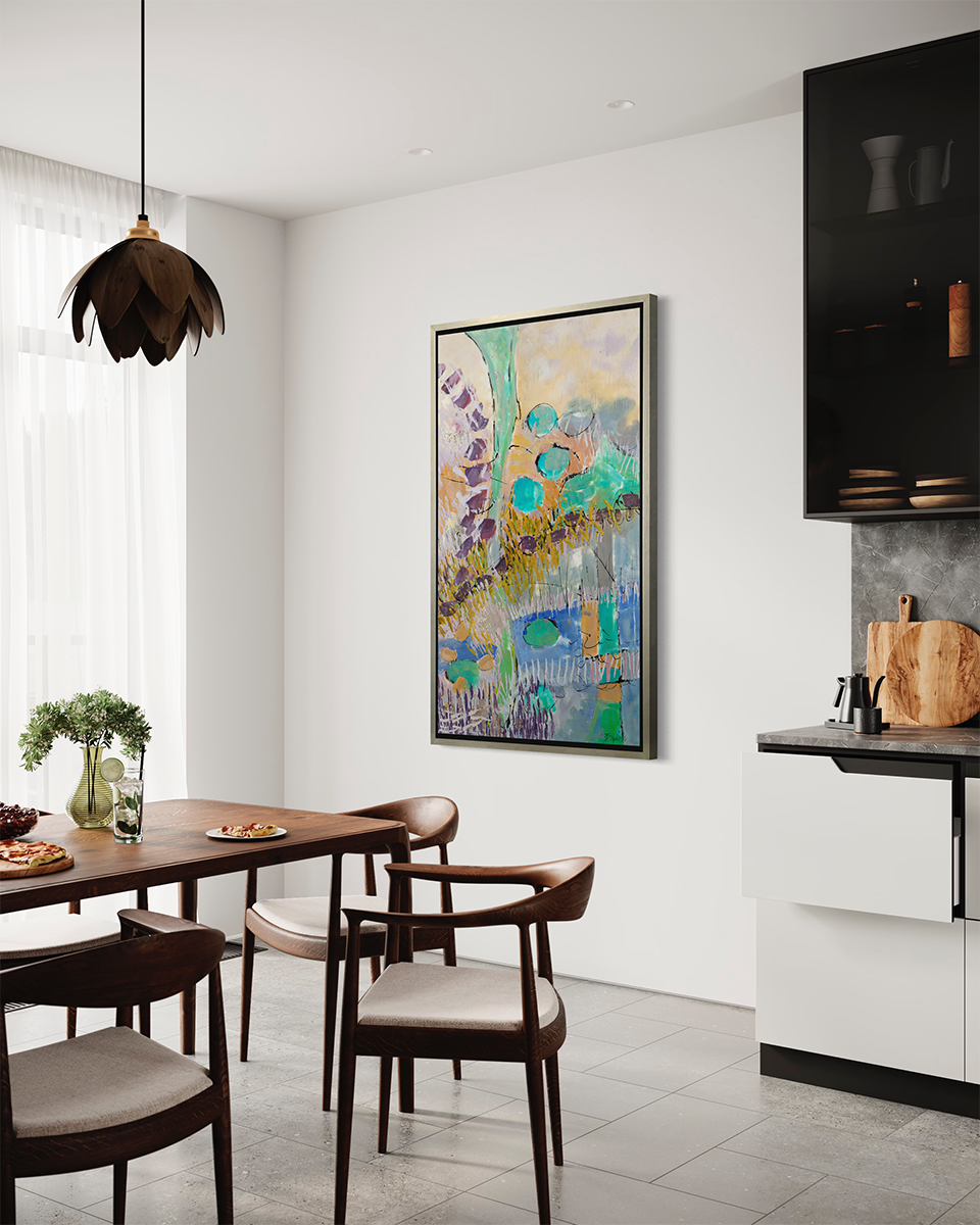 A teal, orange, purple and yellow abstract landscape print in a silver floater frame hangs on a white wall across from a dark wood dining table with four chairs and next to a grey marbled kitchen counter, black top cabinets and white bottom cabinets.