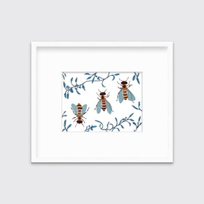 A print of three bees surrounded by blue ferns in a white frame with a mat.