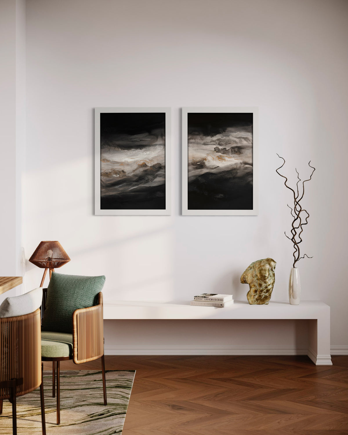 Smoky-Eyes-1&2 with White Frames-on-a-wall over a white bench with books, whit vase with twigs and a gold sculpture.