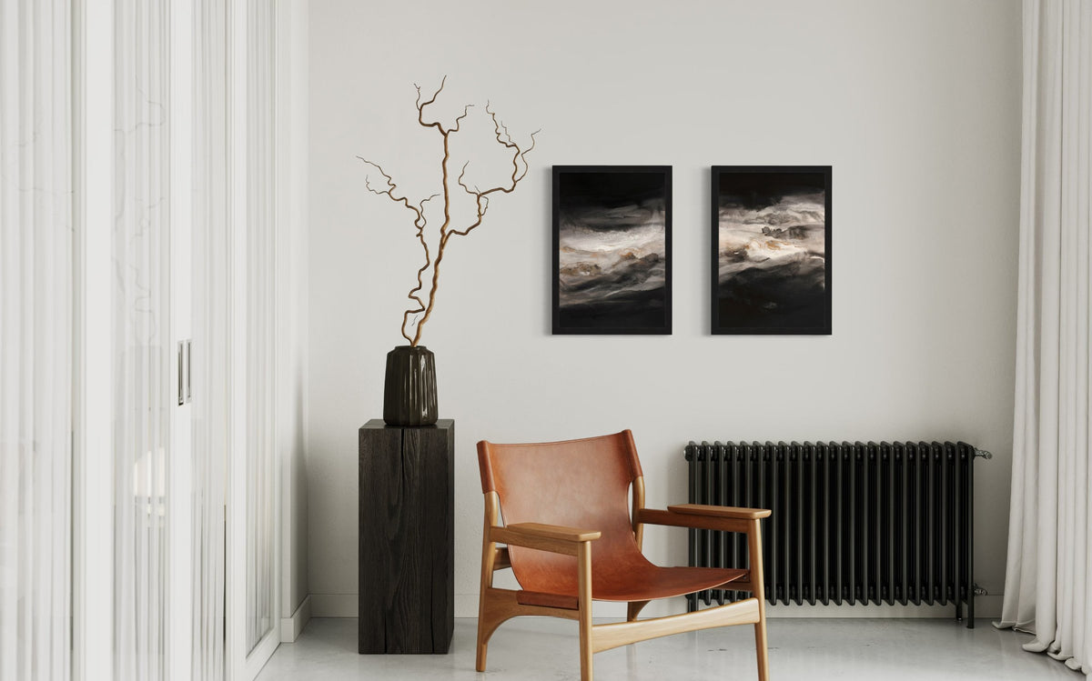 Smoky-Eyes-1&2_Black-Frame-on-a-wall over black radiator with a chair and a black wooden pedestal holding a black vase and twigs.