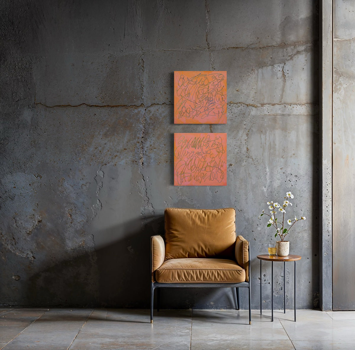 Two square orange abstract text based paintings with carved teal scribbled lines hang on a textured gray concrete wall above a mustard yellow armchair and a small side table with flowers.