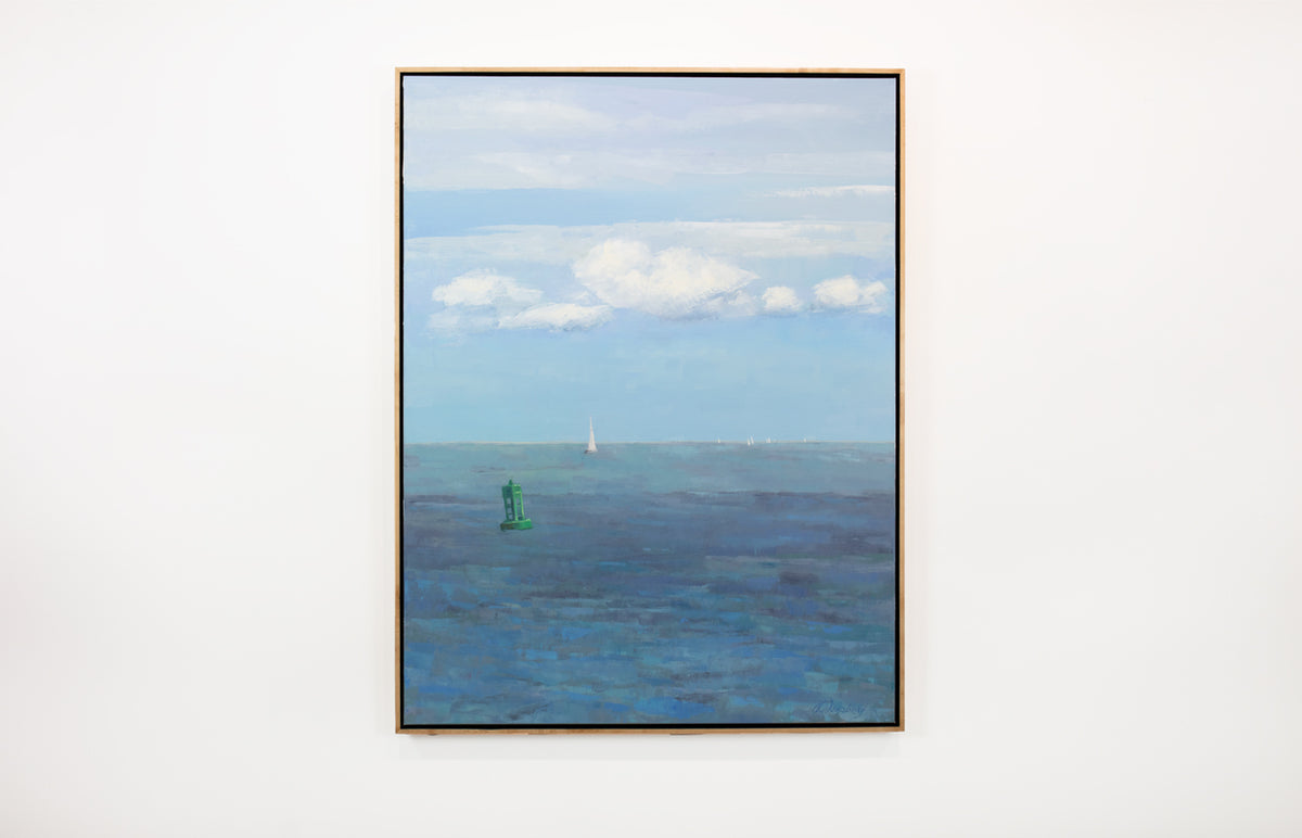 A blue, white and green coastal landscape painting by Molly Doe Wensberg hangs in a light wood floater frame on a white wall.