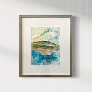 An abstract landscape matted and framed in a silver frame hangs on a white wall.