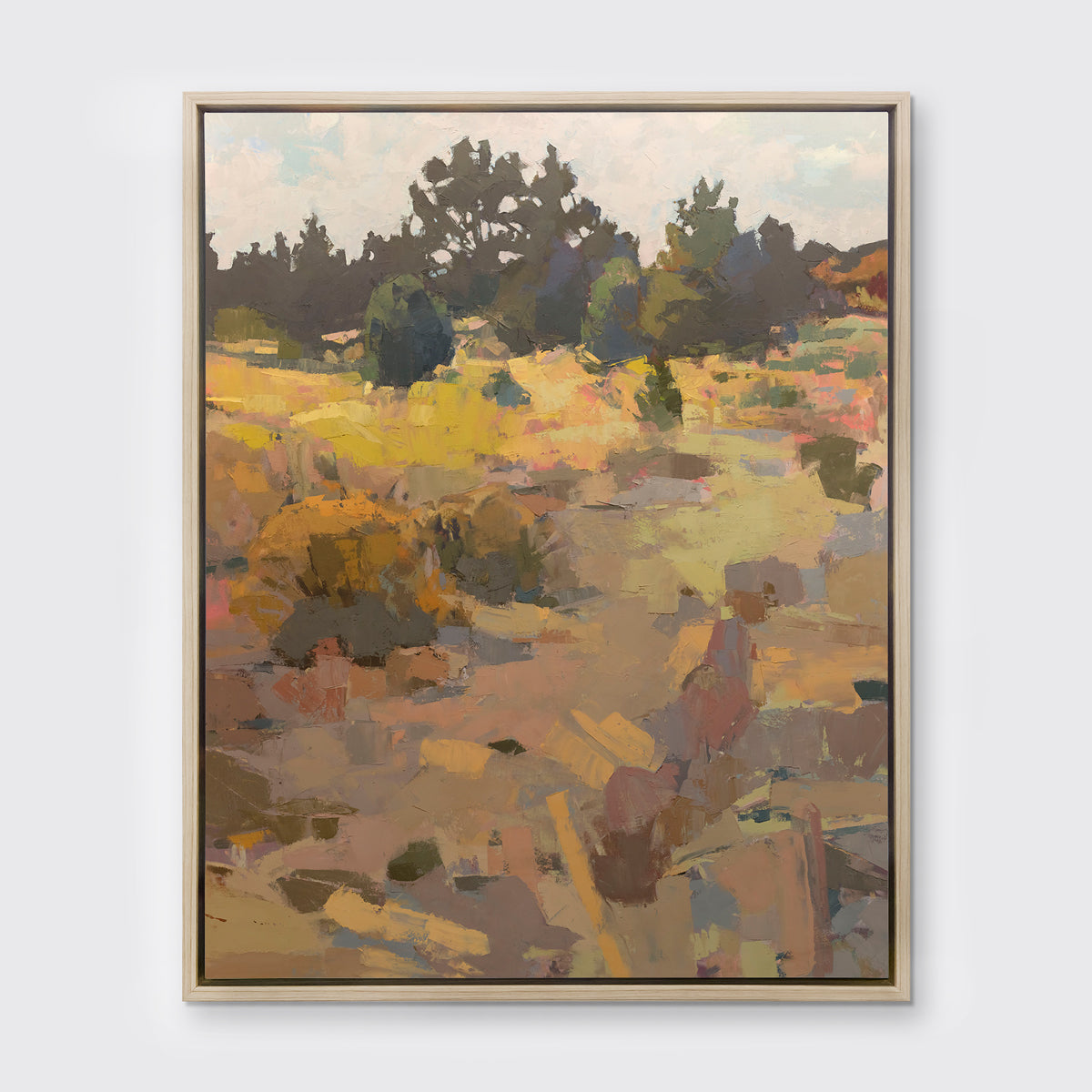 An earth-toned abstracted landscape art print framed in a white oak frame hangs on a white wall.