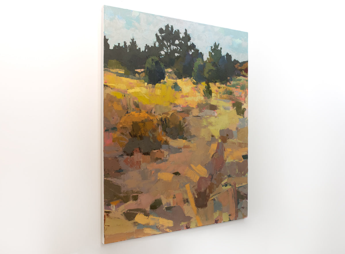 A warm-toned abstracted landscape painting hangs on a white wall.