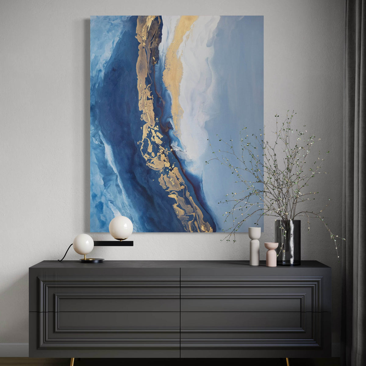 Abstract painting with blue, gold, and white on a wall above a dark cabinet.