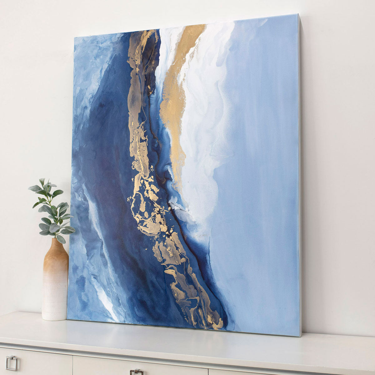 Abstract art painting with blue and gold tones on a white wall