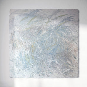 An original textured abstract painting with light blue, gray, and white tones on a white wall.