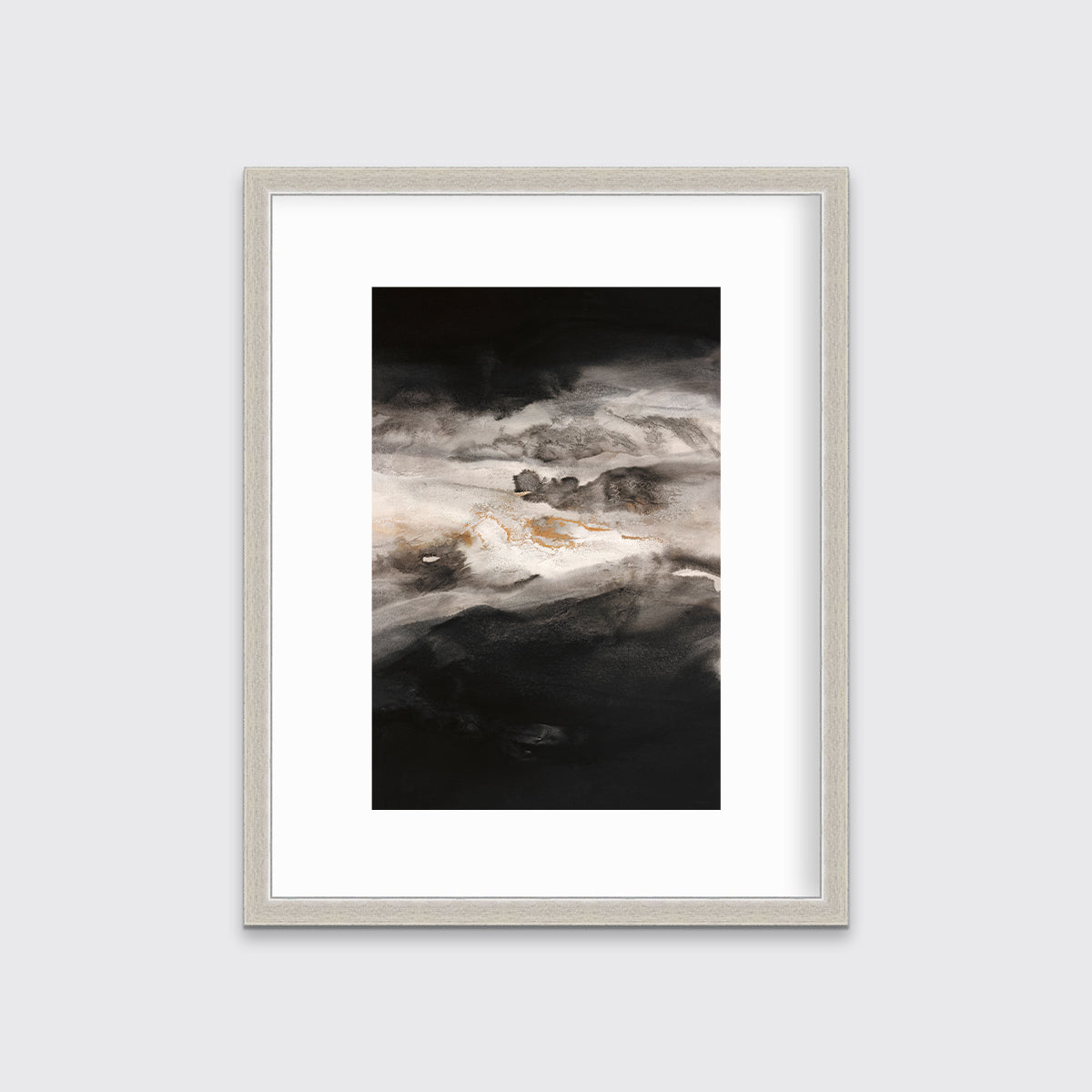 A black, white, beige and gold abstract print in a silver frame with a mat hangs on a white wall.