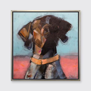 A brown, white, pink and blue abstract dog print in a silver floater frame hangs on a white wall.