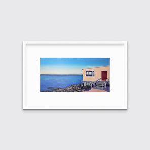 A contemporary seascape print in a white frame with a mat hangs on a white wall.