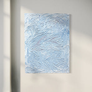 A blue and white textured painting hangs on a white wall.
