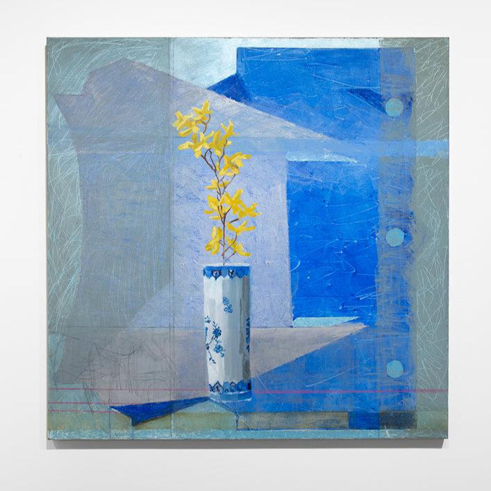 An abstracted blue painting with a vase with yellow flowers in the foreground hangs on a white wall.