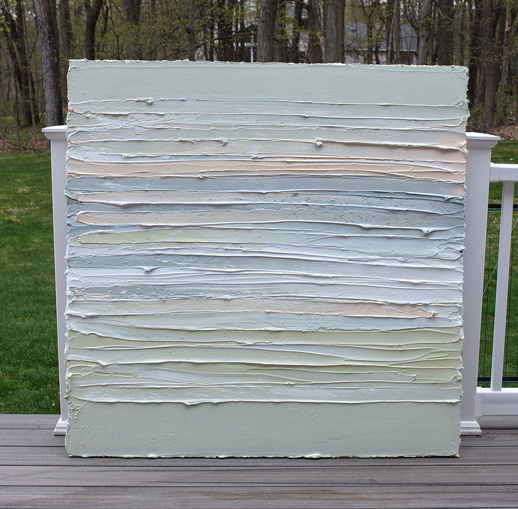 A peach, grey, white, celadon and sage green thickly textured painting leaning outside on a deck in natural light by Teodora Guererra.