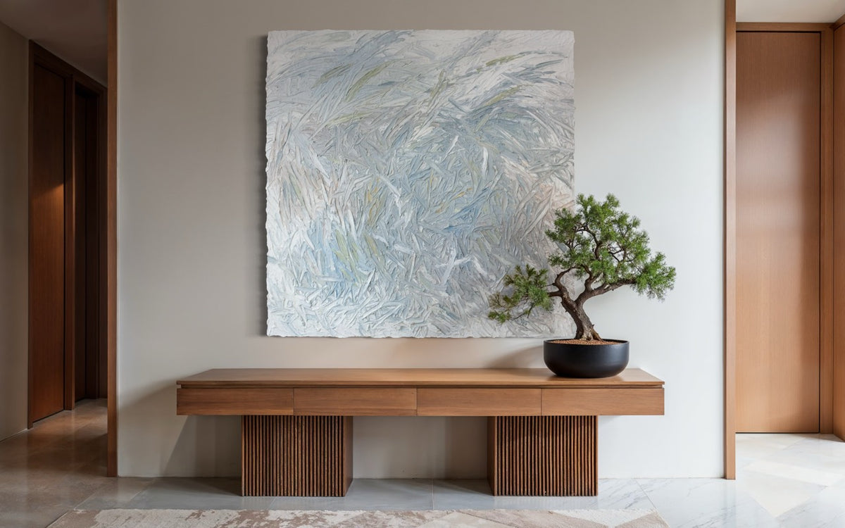 An original abstract painting with thick texture by artist Teodora 'Teo' Guererra hanging on a wall above a wooden console table with a bonsai tree.