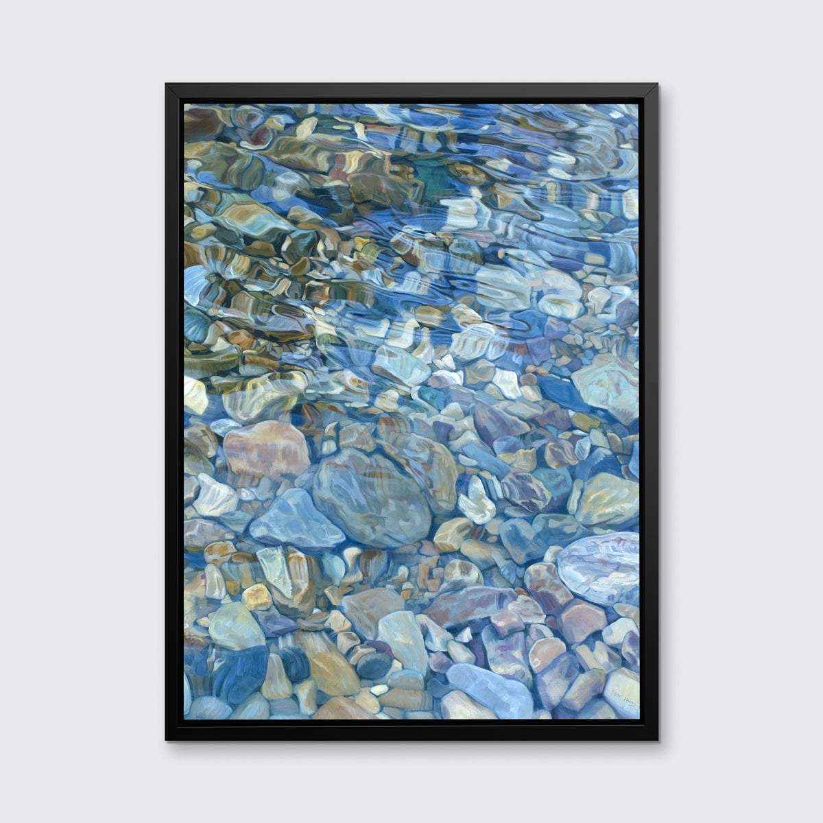 Abstracted river rocks under water hangs in a black floater frame on a light grey wall.