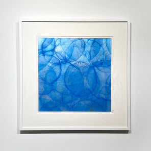 Framed abstract blue artwork on a white wall